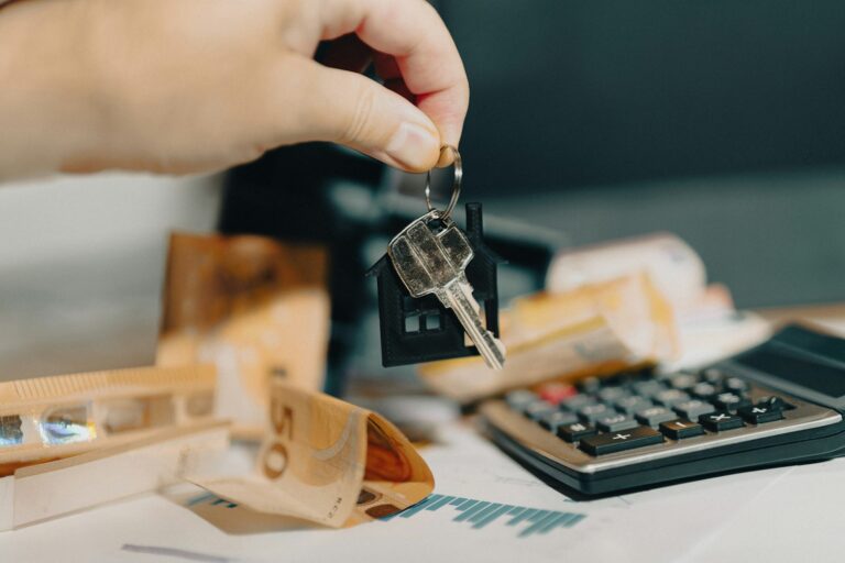 a house key in front of a calculator and money